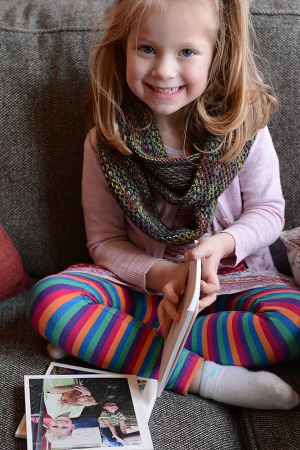 A little girl looking at books on a couch.