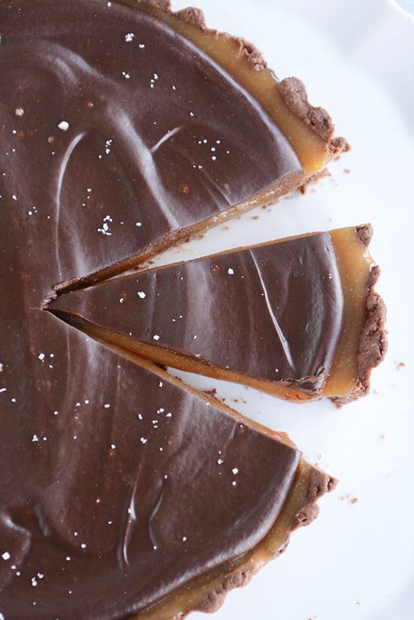 Top view of a chocolate caramel tart with a slice cut out. 