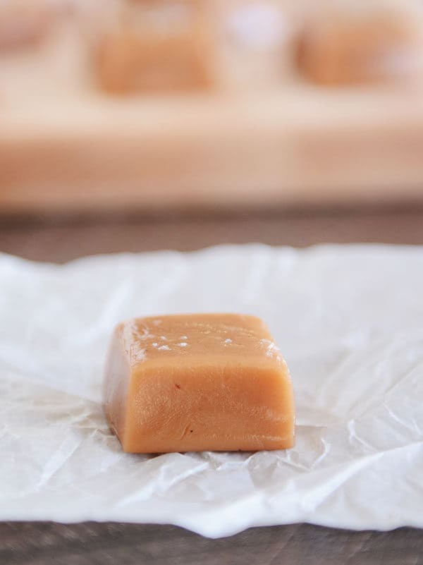 An unwrapped salted vanilla bean caramel on a piece of parchment.