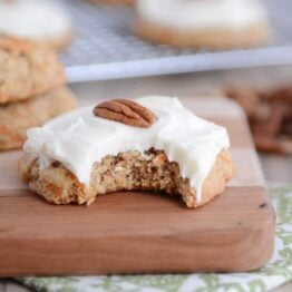 Frosted carrot cake cookie with a bite taken out.