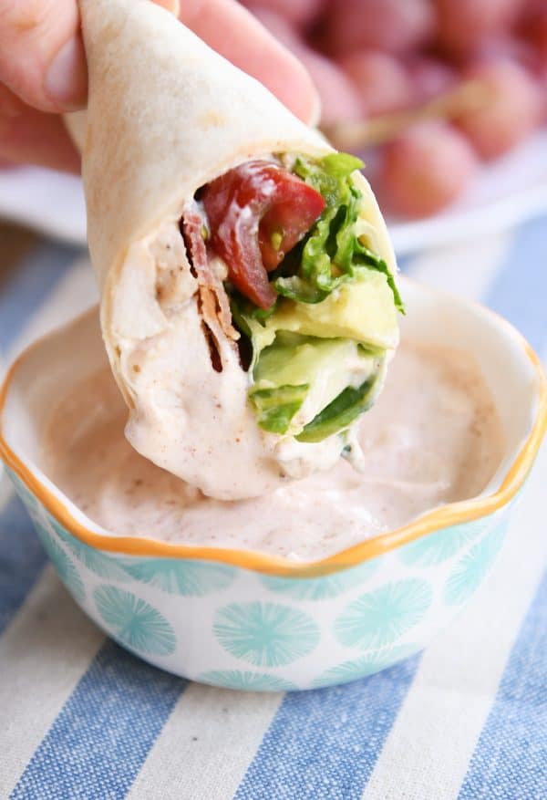 Dipping chicken BLT burritos in creamy dipping sauce.