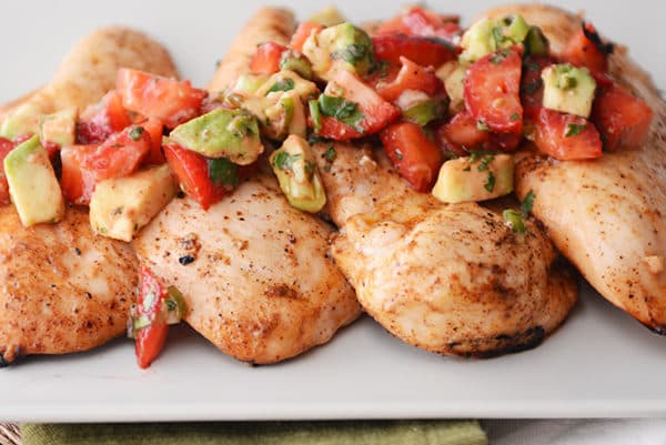 Four grilled chicken breasts topped with a strawberry-avocado salsa.