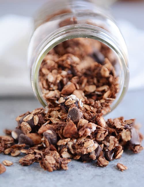 Chocolate granola spilling out of a mason jar.