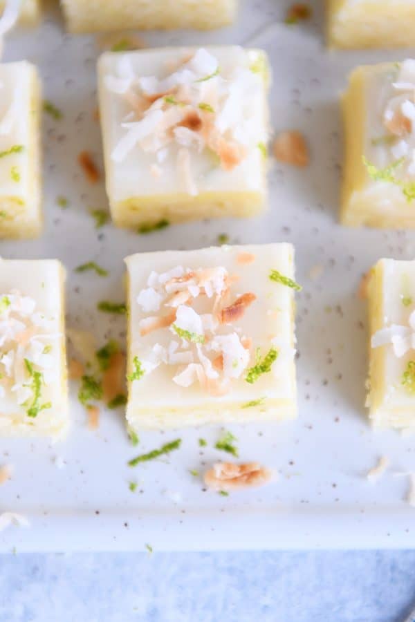Top down view of toasted coconut lime bars on white platter.