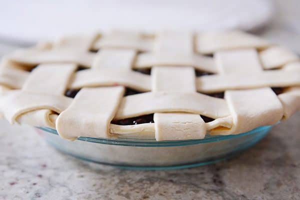 A pie with a lattice pie crust in a glass dish.