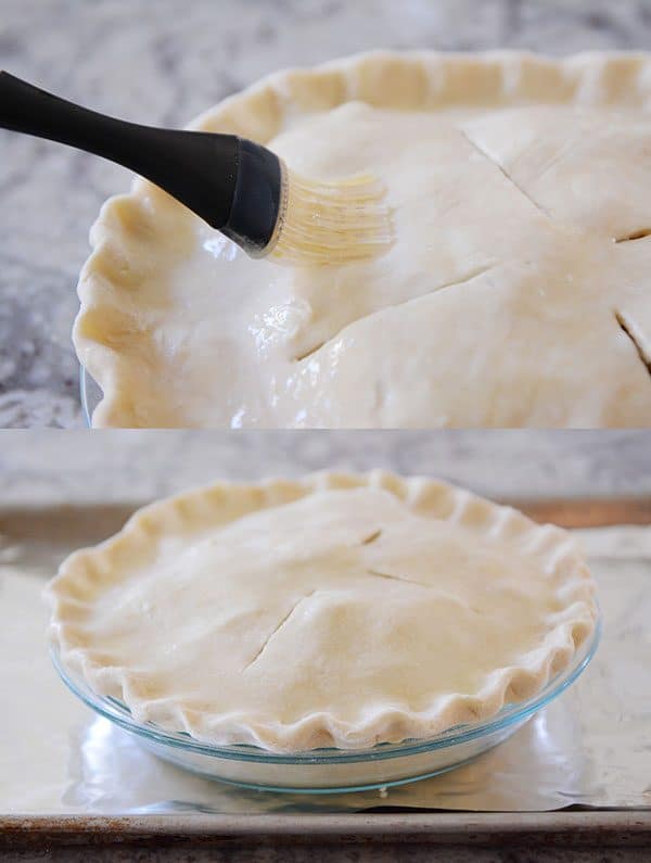 An uncooked pie crust getting brushed with egg whites.