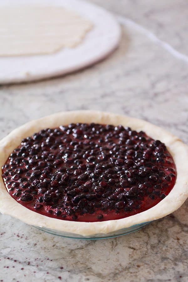 An uncooked pie filled with a berry mix.