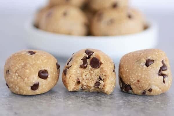 Three cookie dough bites lined up in a row, the middle one has a bite taken out.