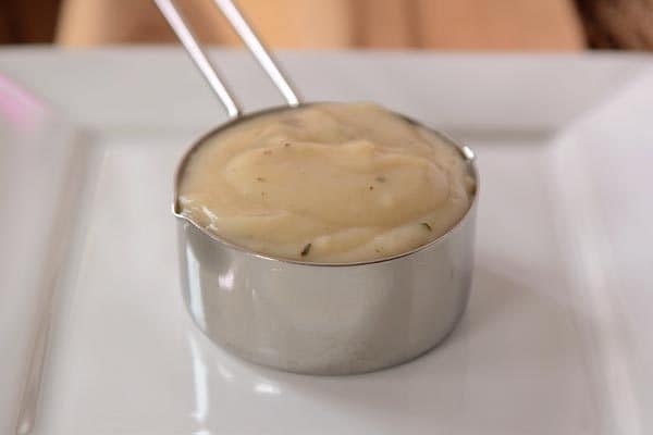 A metal measuring cup full of cream of chicken soup.