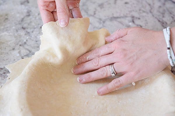 Pie crust getting put into a pie dish.