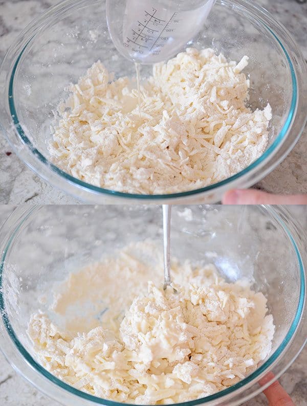 Cold water getting poured into pie dough ingredients.