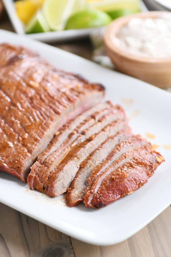 Sliced steak for steak fajitas on white platter.