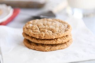 Three gingerbread oatmeal cookies stacked on white napkin.