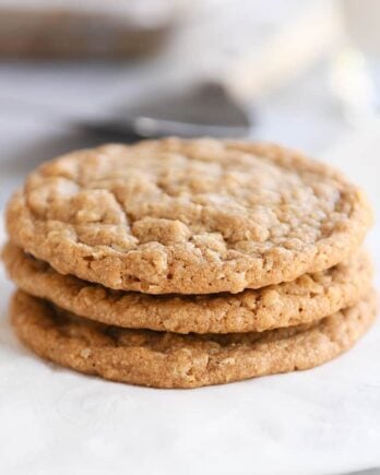 Three gingerbread oatmeal cookies stacked on white napkin.