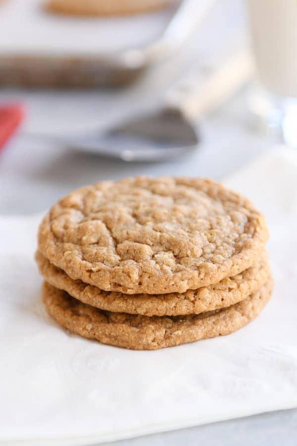Three gingerbread oatmeal cookies stacked on white napkin.