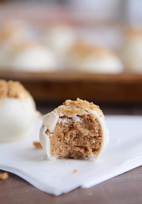 A white chocolate dipped gingerbread truffle with a bite taken out.