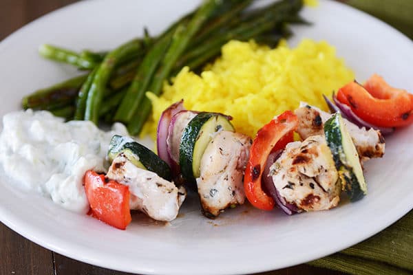 Grilled vegetables and veggies next to green beans and sauce. 