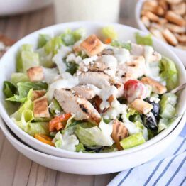 White bowl of chopped Greek chicken salad with tzatziki dressing.