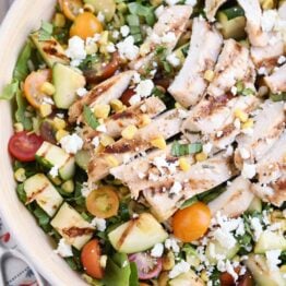 Top down view of grilled chicken orzo salad in white serving bowl.