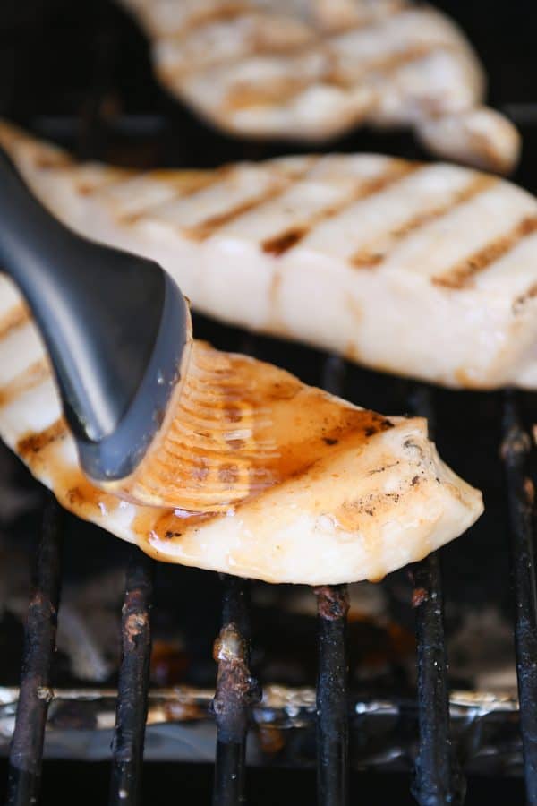 Chicken on grill brushed with sweet and sour sauce.