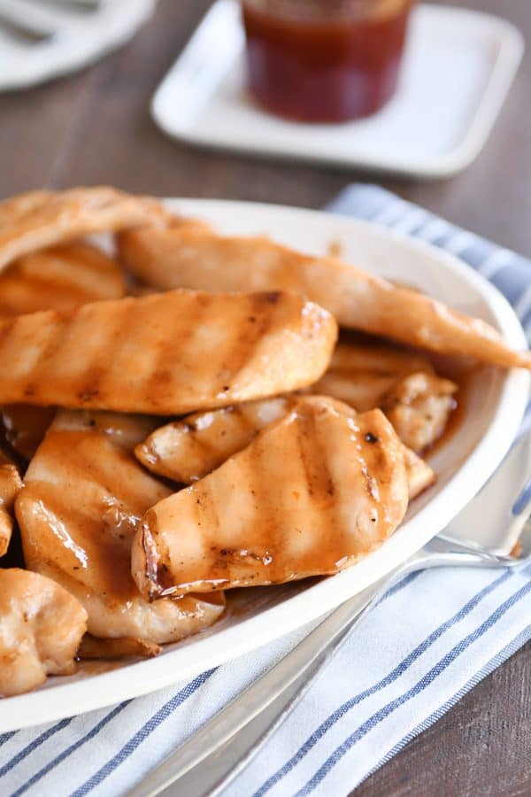 White platter of grilled sweet and sour chicken pieces.