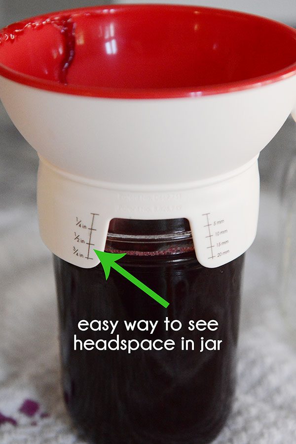 A funnel of top of a mason jar of grape juice.
