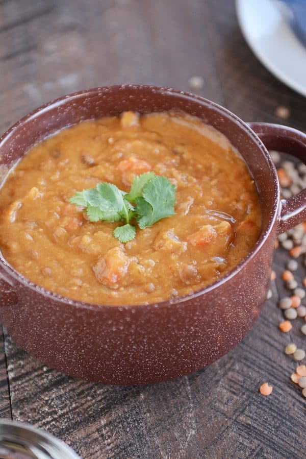 A red pot filled with thick and creamy lentil soup. 