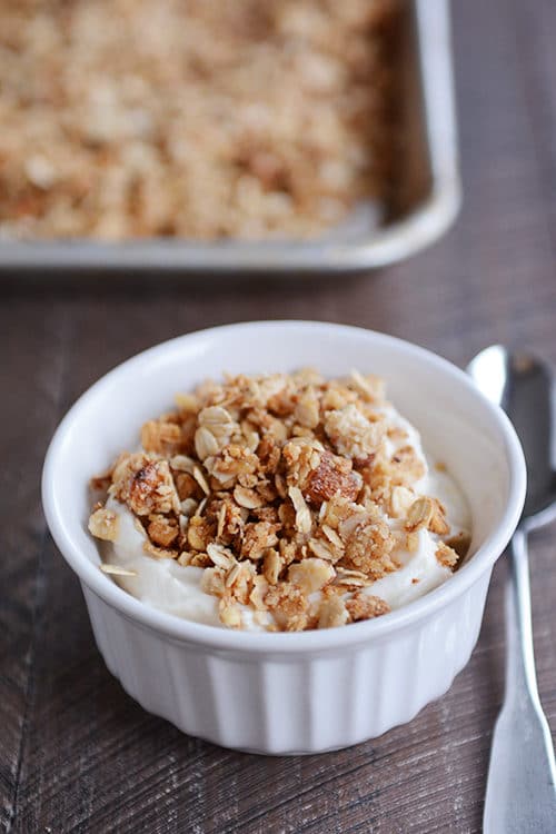A white ramekin filled with yogurt topped with granola.