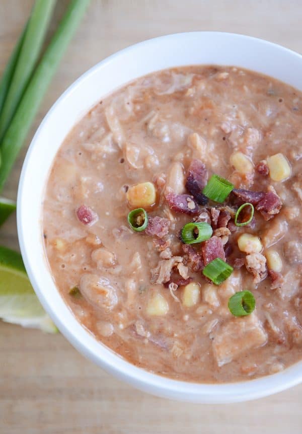 Top view of a white bowl full of white bean chicken chili topped bacon and chives.