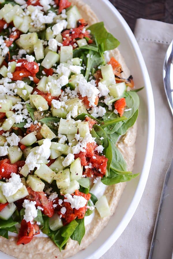 Top down view of a white oval bowl of Greek hummus dip. 