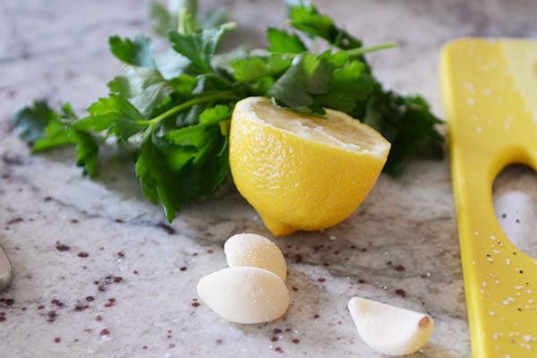 Three garlic cloves, half a lemon, and sprigs of parsley. 