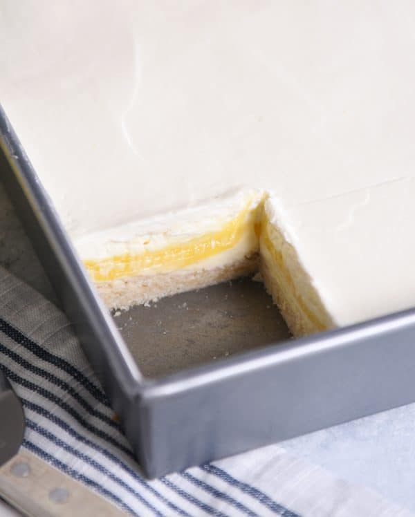 Lemon truffle shortbread bars in 9X13-inch metal pan with piece cut out.