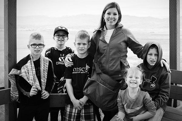 A mom standing with her five kids in front of a big window.