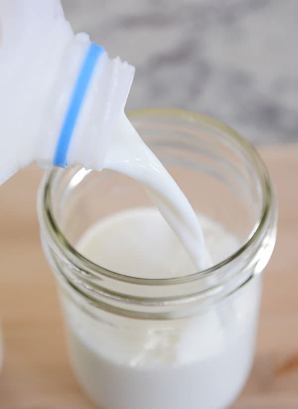 Milk getting poured into a mason jar.