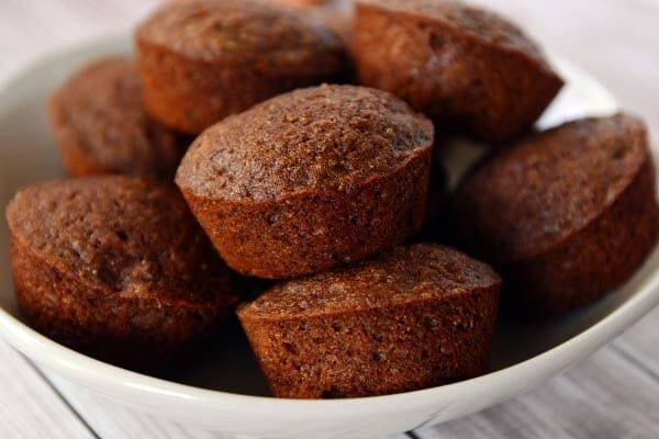 A white plate full of golden brown cooked muffins. 