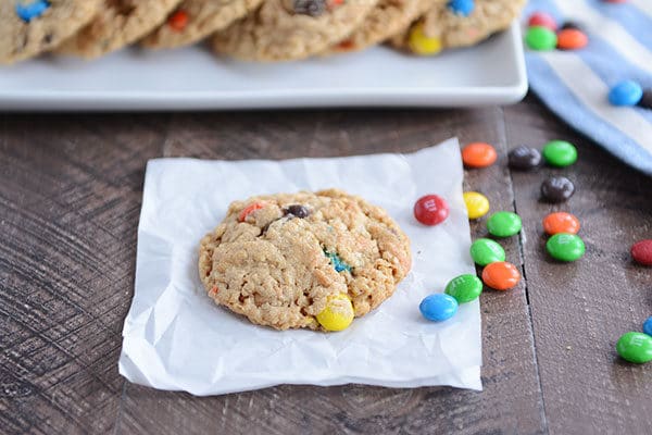 An M&M cookie on a piece of parchment paper with M&M's sprinkled on the side.