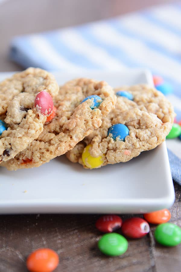 A white tray with three oat M&M cookies and a few M&M's sprinkled around the side.