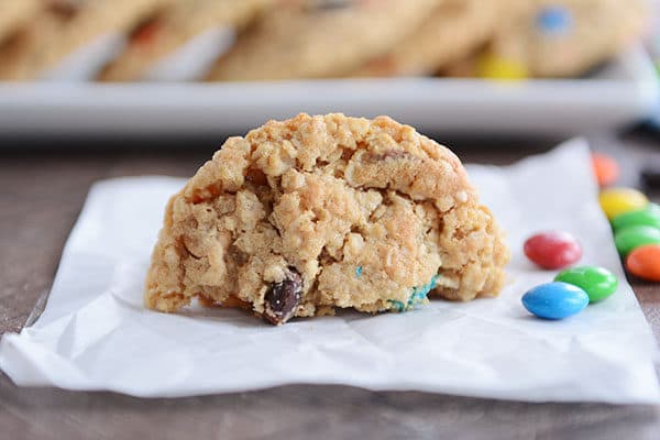 A half of an M&M cookie on a piece of parchment with a few sprinkled M&M's on the side.