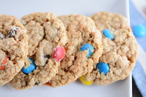 Four M&M oat cookies lined up side-by-side on a white platter. 
