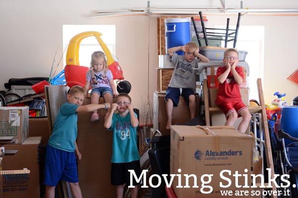 Five little kids making silly faces surrounded by moving boxes.
