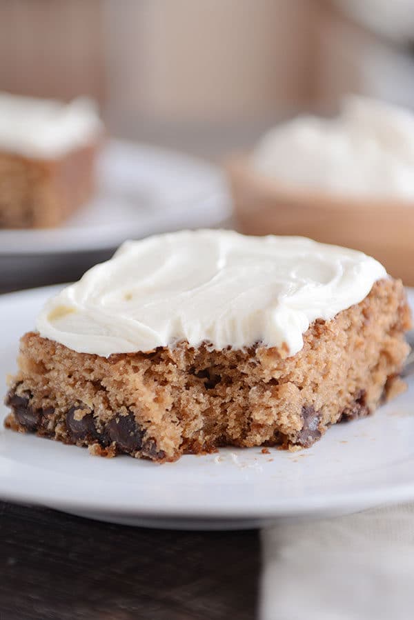 A piece of cream cheese frosted oatmeal chocolate chip cake with a bite taken out.