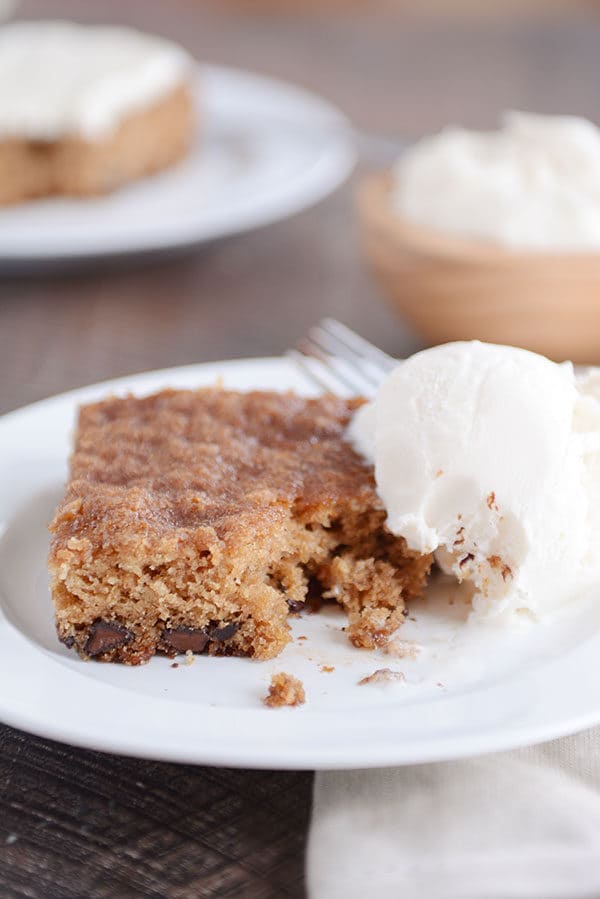 A piece of chocolate chip cake with a bite taken out next to a scoop of vanilla ice cream.
