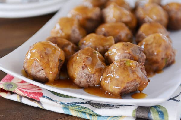A white platter of meatballs with an orange glaze poured over the top. 
