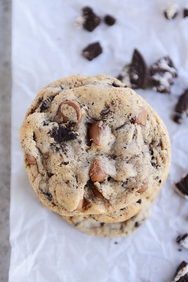 Chocolate chip and Oreo cookies stacked on top of each other on a piece of parchment.
