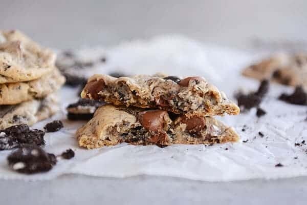A chocolate chip Oreo cookie split in half on a piece of parchment paper.