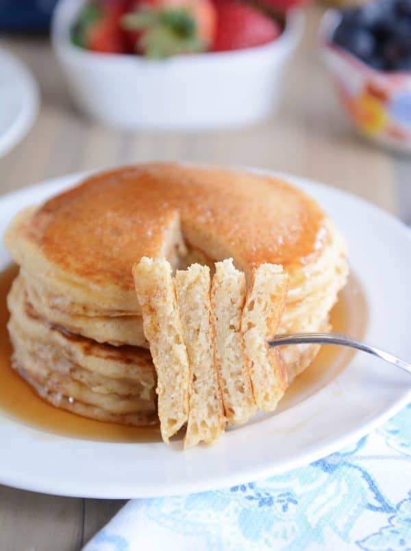 A stack of pancakes with a fork taking a bite out.