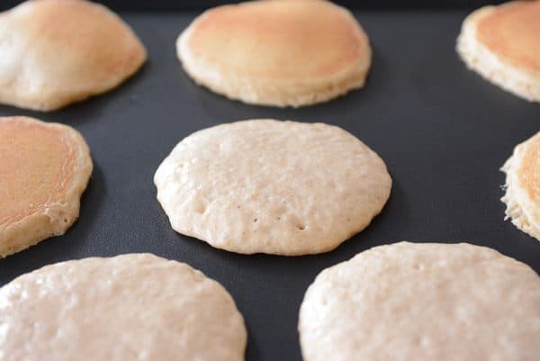 Pancakes cooking on a griddle.