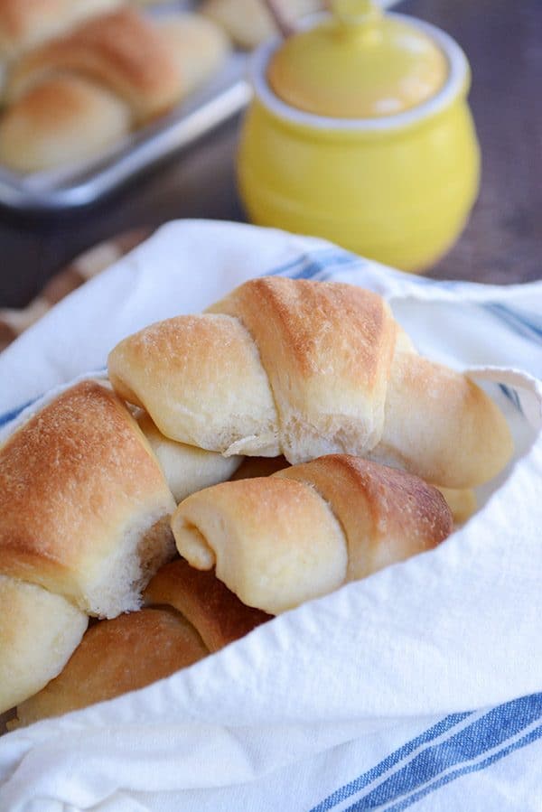 A napkin-lined basket of baked crescent rolls.