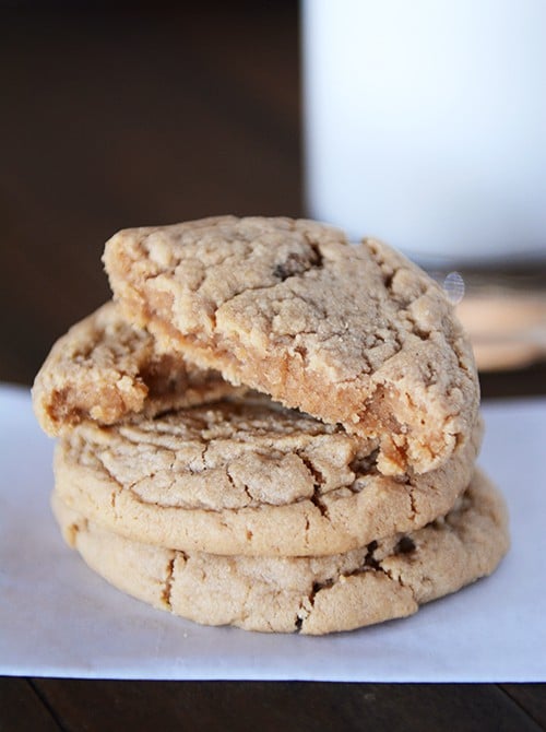 A stack of peanut butter cookies with the top cookie split in half. 
