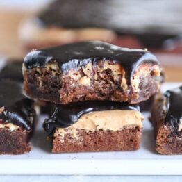 Stack of peanut butter marshmallow fudge brownies with bite taken out.